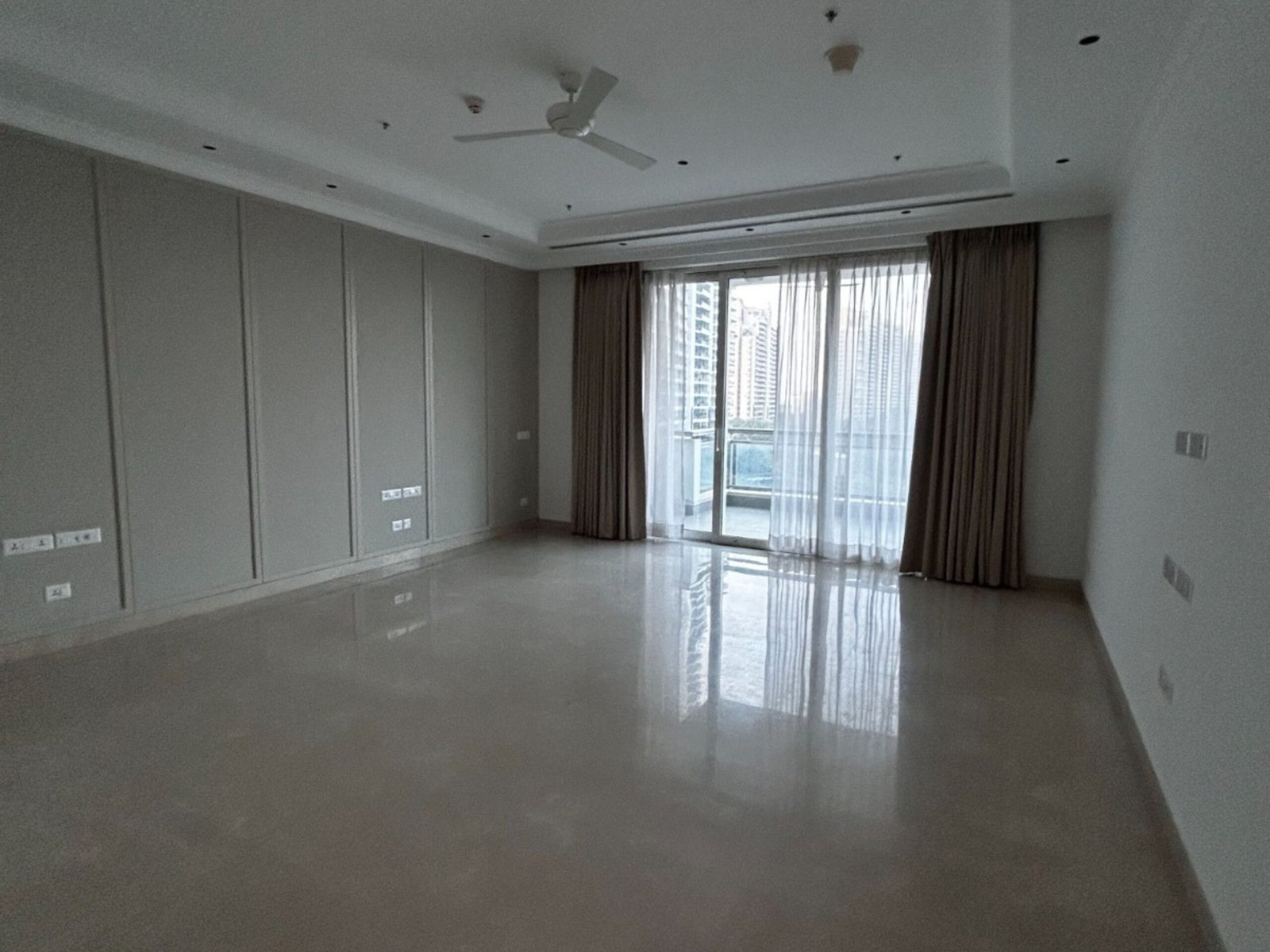 Spacious bedroom with balcony view in a 7400 sq ft DLF Camellias apartment